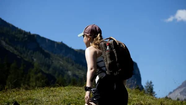 a woman with a backpack walking up a hill