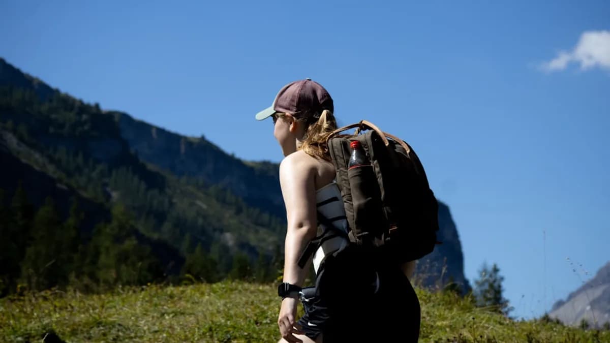 a woman with a backpack walking up a hill