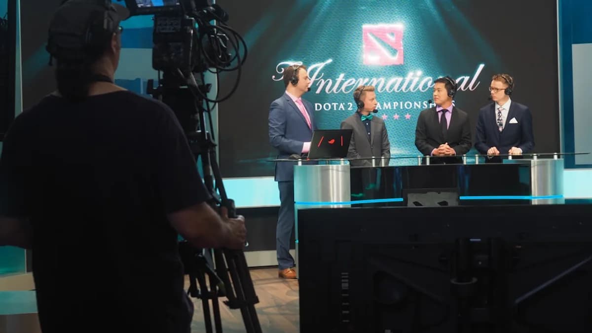 Three men in suits being filmed for dota 2 competition.