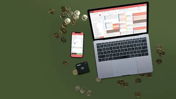 Laptop, phone, and coins on a green surface