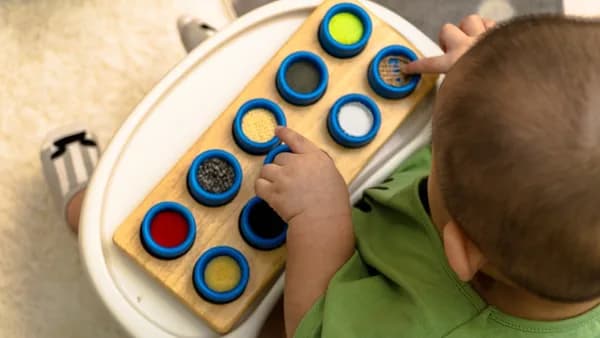 boy in green t-shirt playing with blue and white round plastic toy