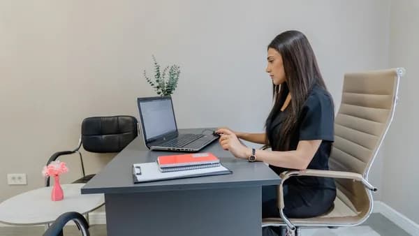 Woman working on laptop at desk in office.