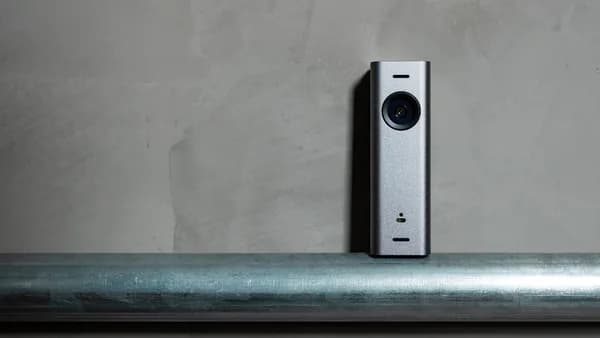 a silver camera sitting on top of a metal pole