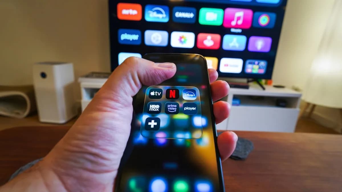 Hand holding smartphone controlling smart TV apps