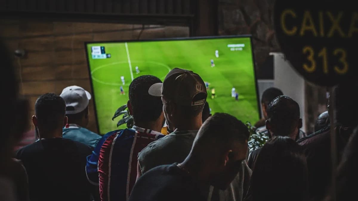 A group of people watching a soccer game on TV