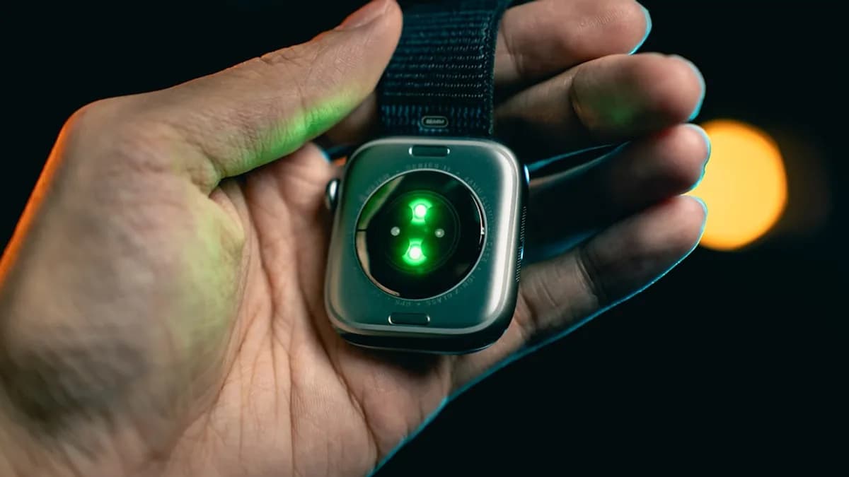 Hand holding smartwatch with glowing green sensor