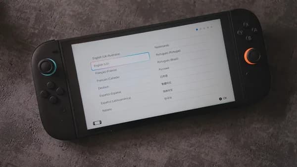 A handheld console displays language options.