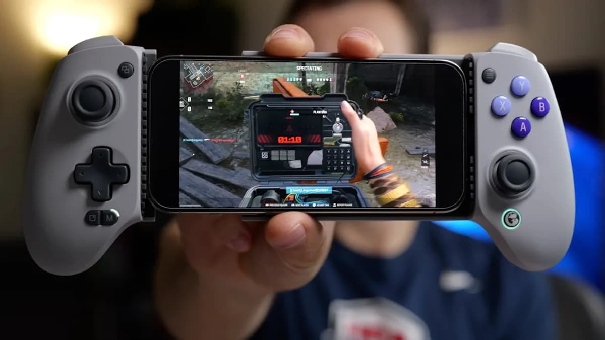 Person holding smartphone with game controller attachment