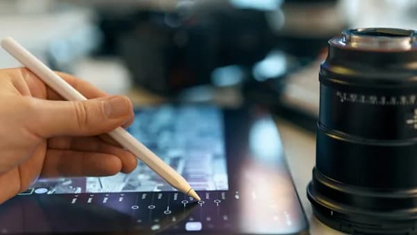 Hand using stylus on tablet near camera lens