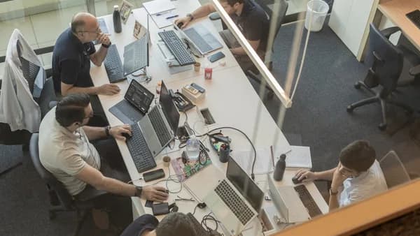 Four people working at desks in a modern office.