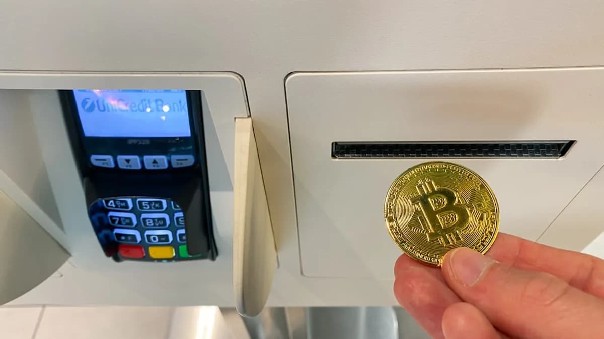 a hand holding a coin in front of a machine
