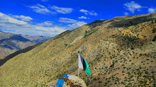 white sailboat on green grass field near mountain under blue sky during daytime