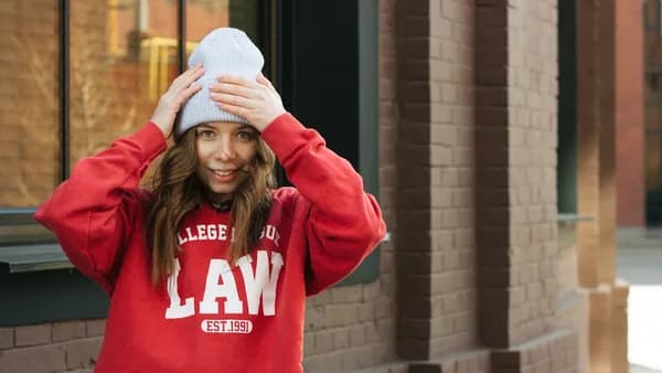 a woman in a red sweatshirt is covering her eyes