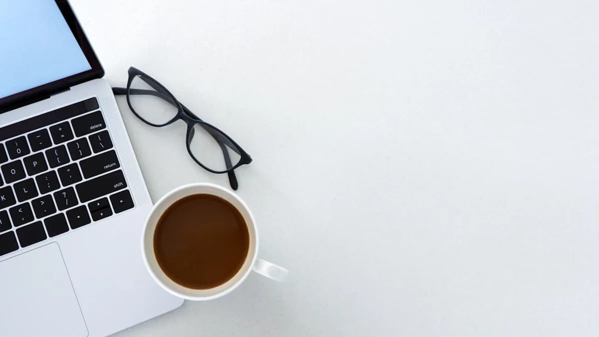 Laptop, coffee, and glasses on a white desk.