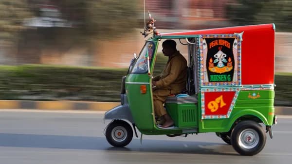 a man driving a green and red truck down a street