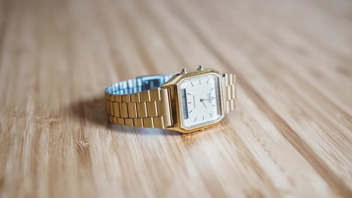 square gold-colored analog watch on brown wooden board