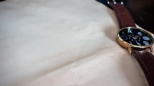 round gold-colored watch with brown leather strap