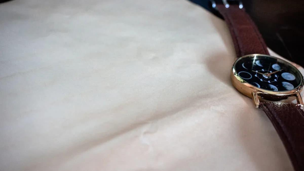 round gold-colored watch with brown leather strap