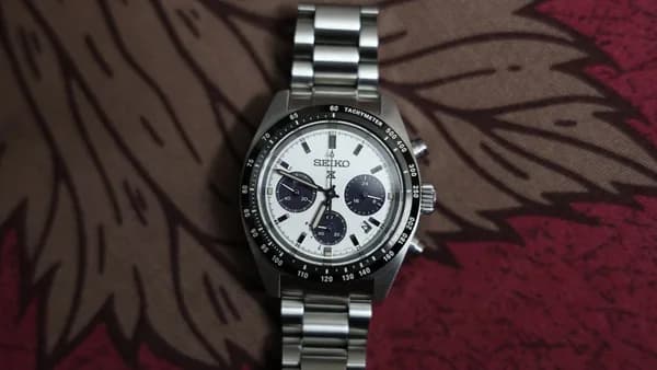 A silver chronograph watch with a white dial.