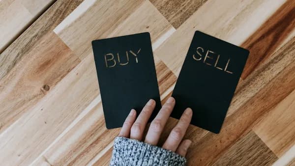 a person holding two small black books with the words buy and sell on them