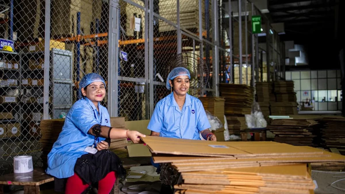 Workers package cardboard boxes in a warehouse.
