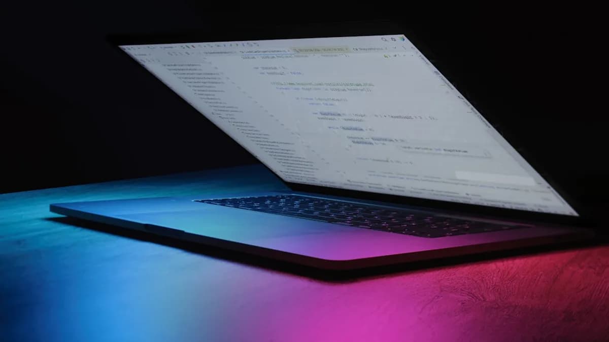 Open laptop with code on screen, neon lighting