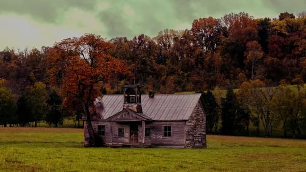 an old house in a field with trees in the background