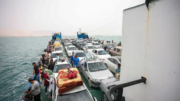 Cars and people on a ferry crossing the ocean.