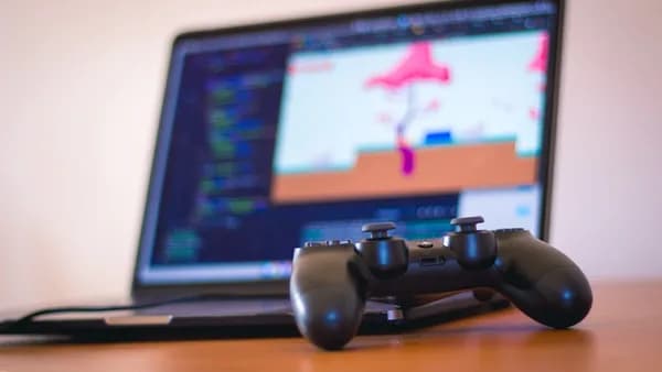 black laptop computer beside controller on brown wooden surface