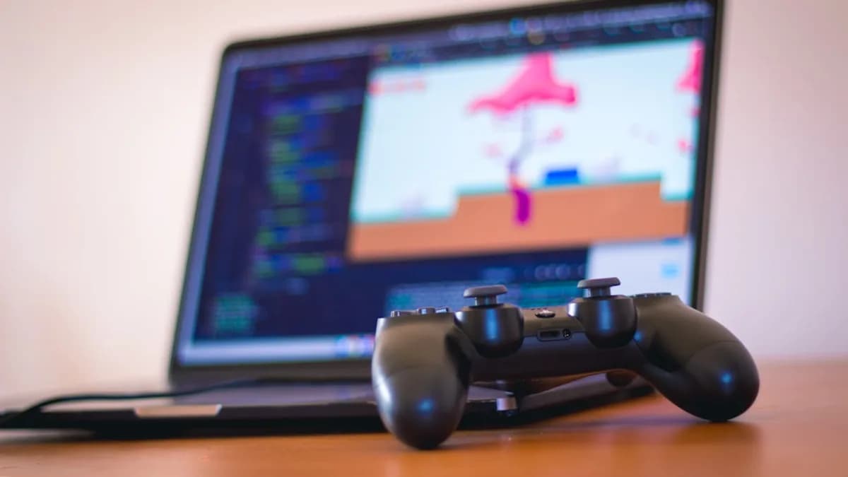black laptop computer beside controller on brown wooden surface