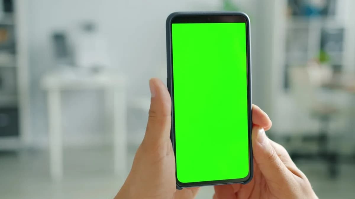 Hands holding a smartphone with a green screen.