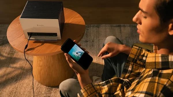 A man uses a phone connected to a projector.