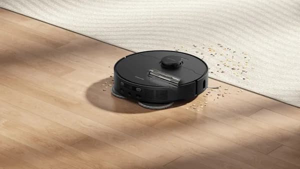 Robot vacuum cleaning spilled water and debris on floor.