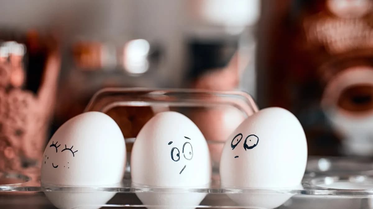 three eggs with faces drawn on them in a carton