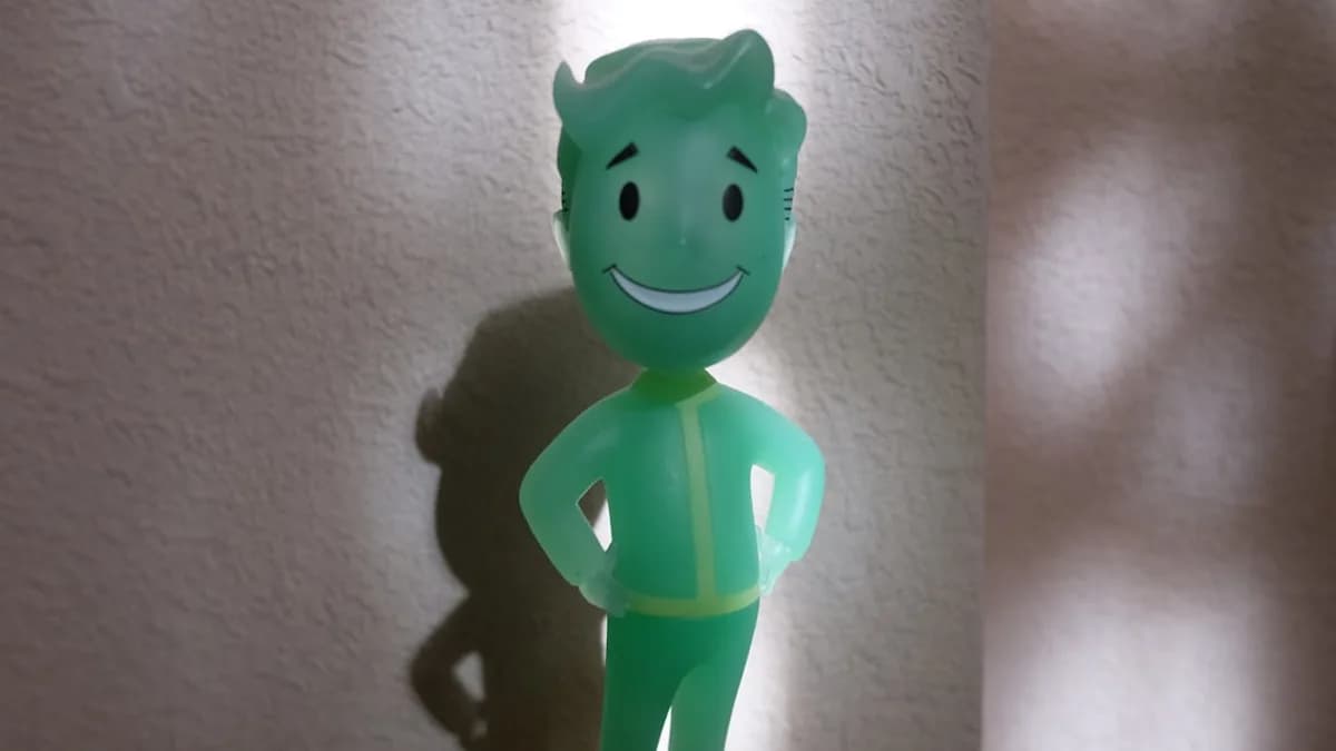 A green plastic figure standing next to a white wall
