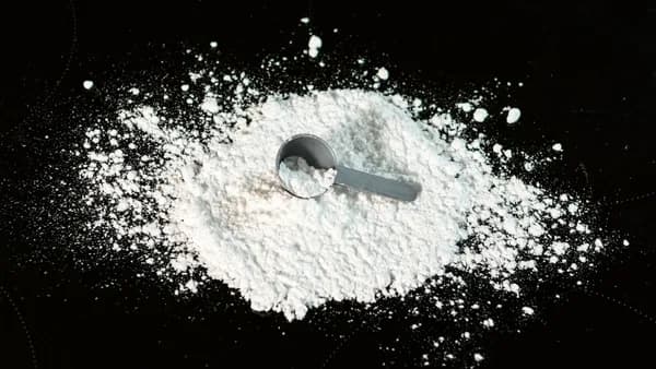 a scoop of powder next to a scoop of sugar