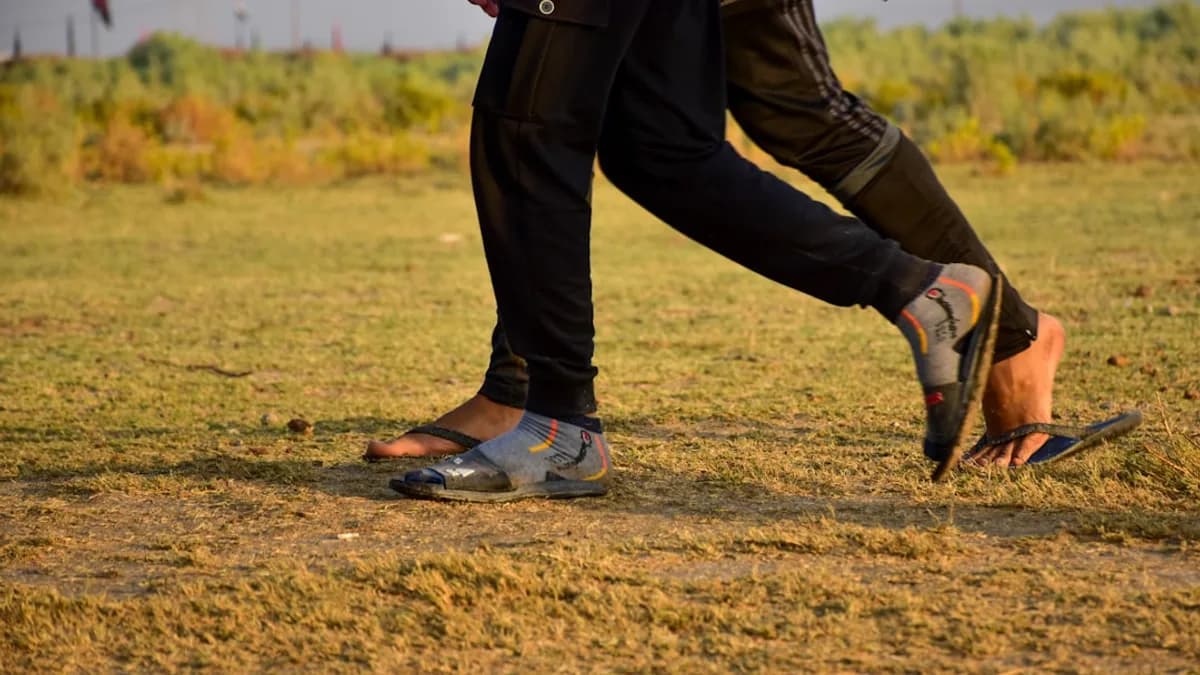 man in black pants and brown leather jacket walking on green grass field during daytime