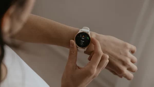A woman holding a smart watch in her hand