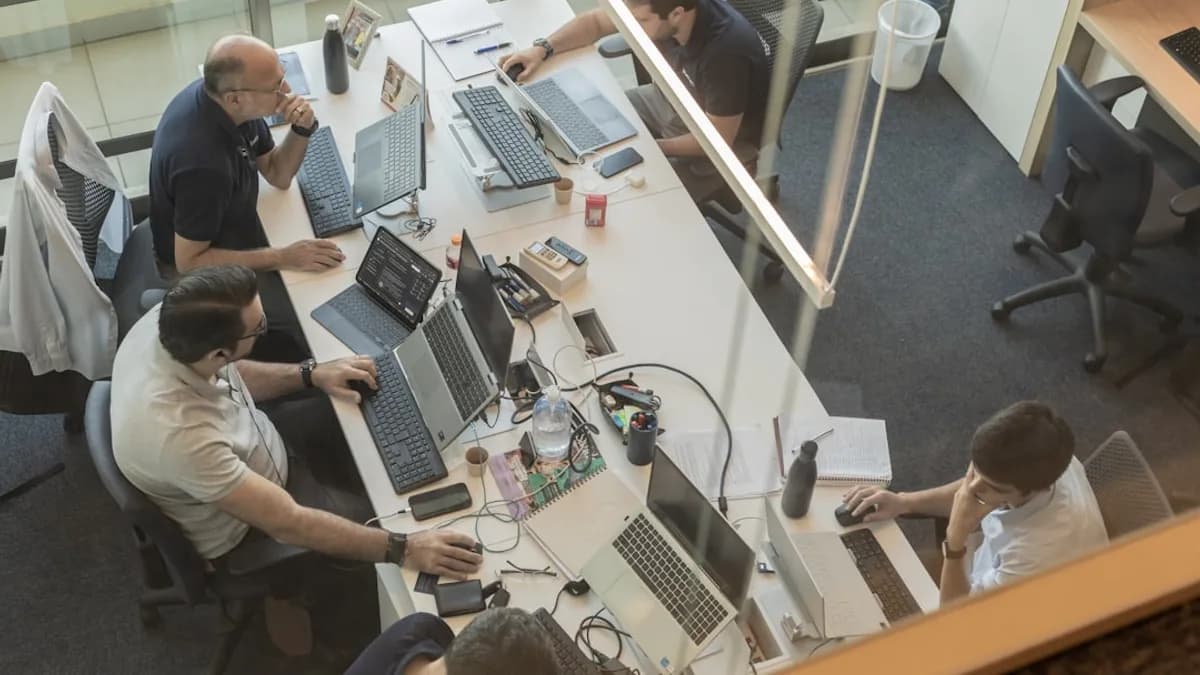 Four people working at desks in a modern office.