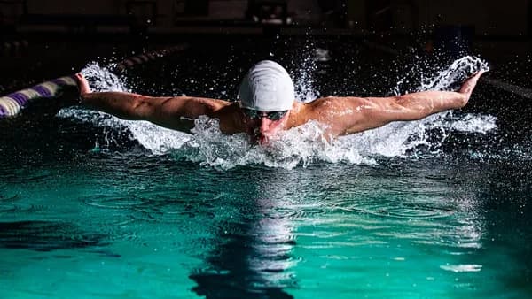 a man swimming in a pool with a hat on
