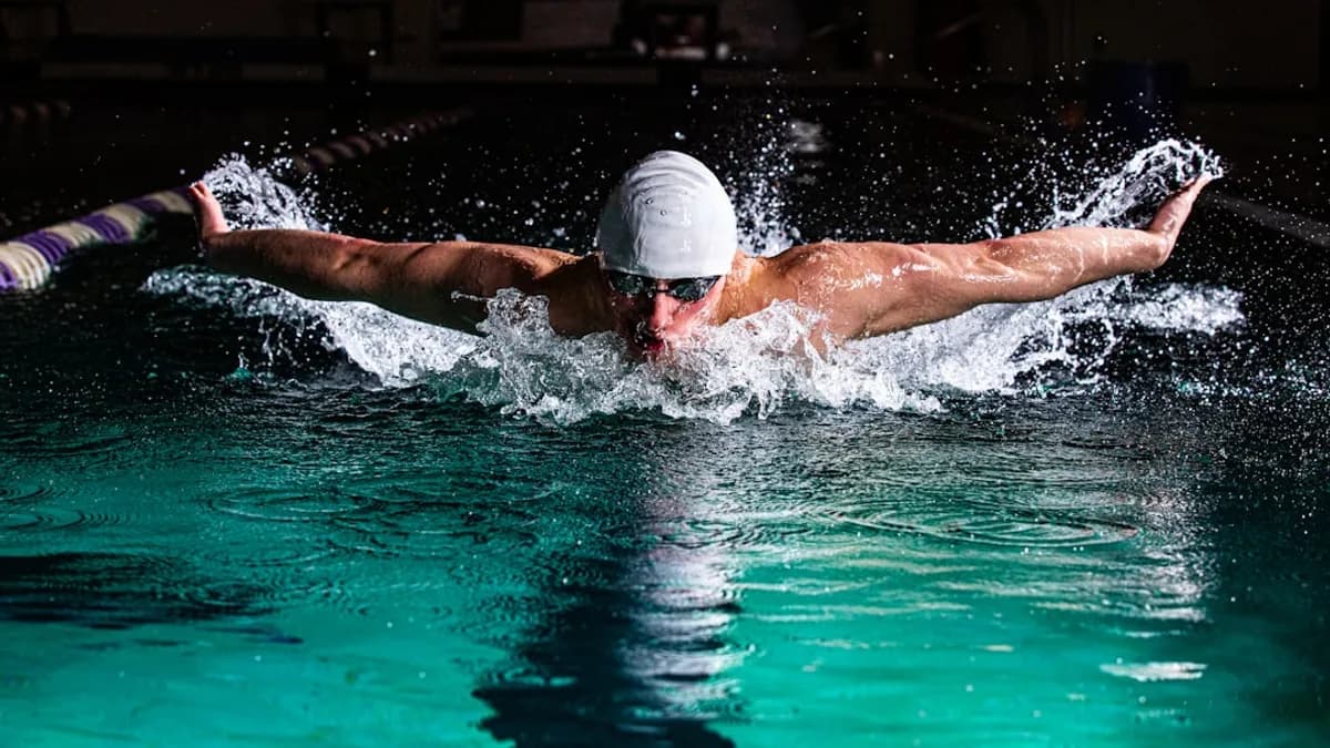 a man swimming in a pool with a hat on