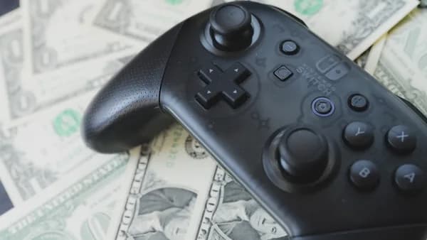 a video game controller sitting on top of a pile of money