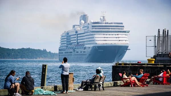 A cruise ship prepares to dock near onlookers.