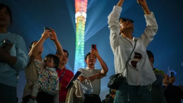 People watching a colorful tower light show at night.