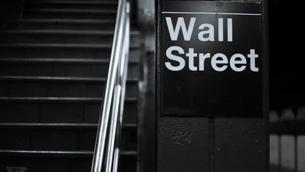 a black and white photo of a wall street sign