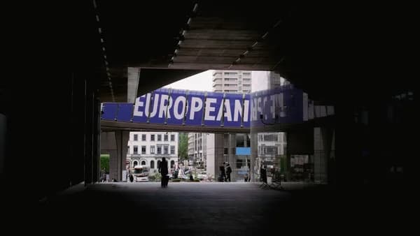 a person walking under a bridge with a european sign above it