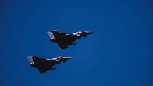 two fighter jets flying through a blue sky