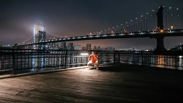 man sitting on dock in front bridge