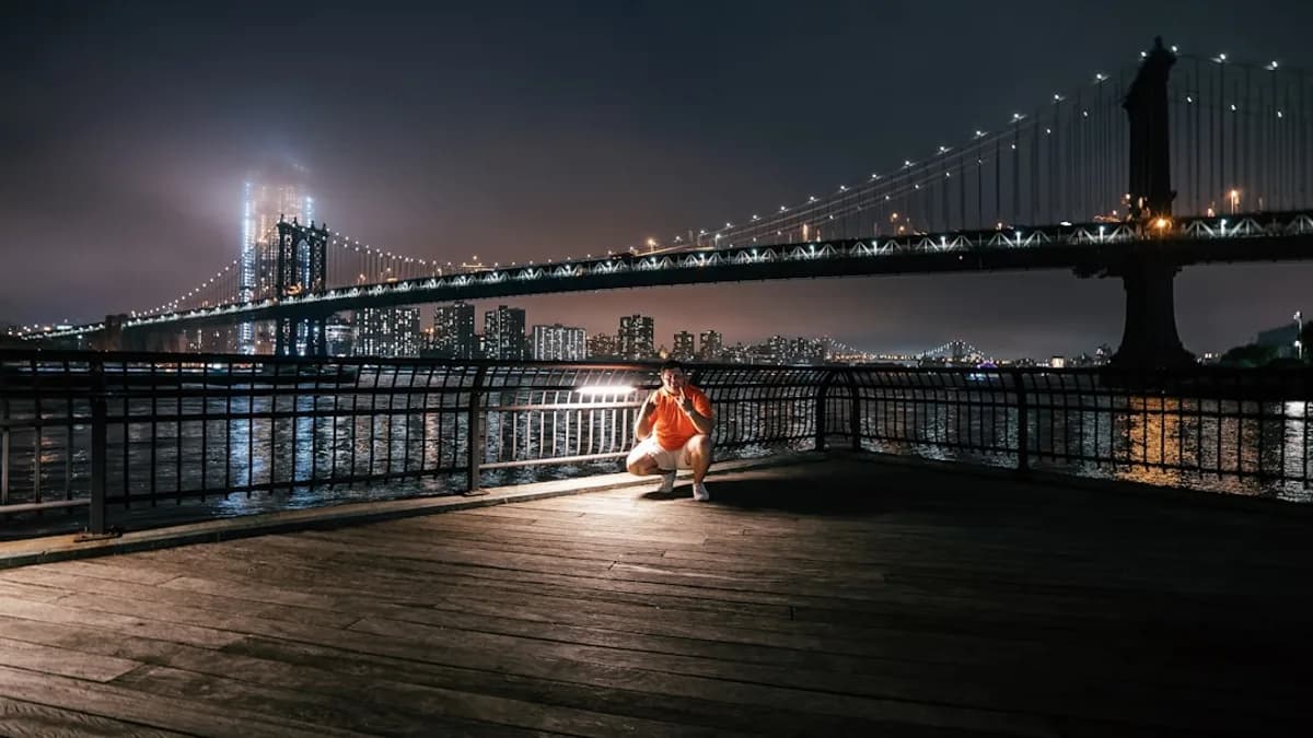 man sitting on dock in front bridge