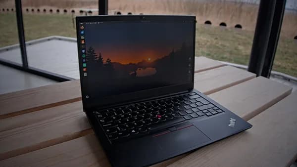 A laptop sits open on a wooden surface.